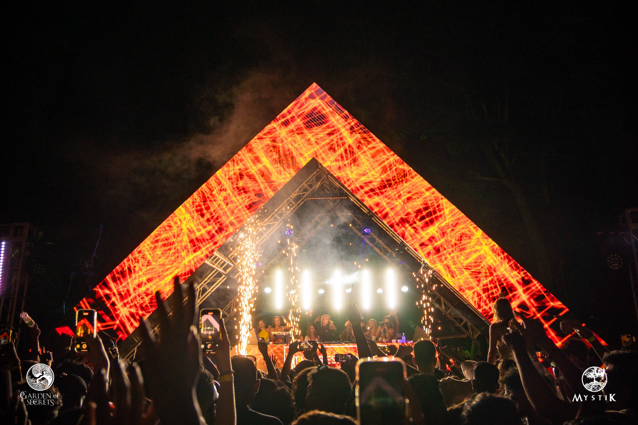 Triangular LED canopy with pyrotechnic spark fountains above the festival crowd at night