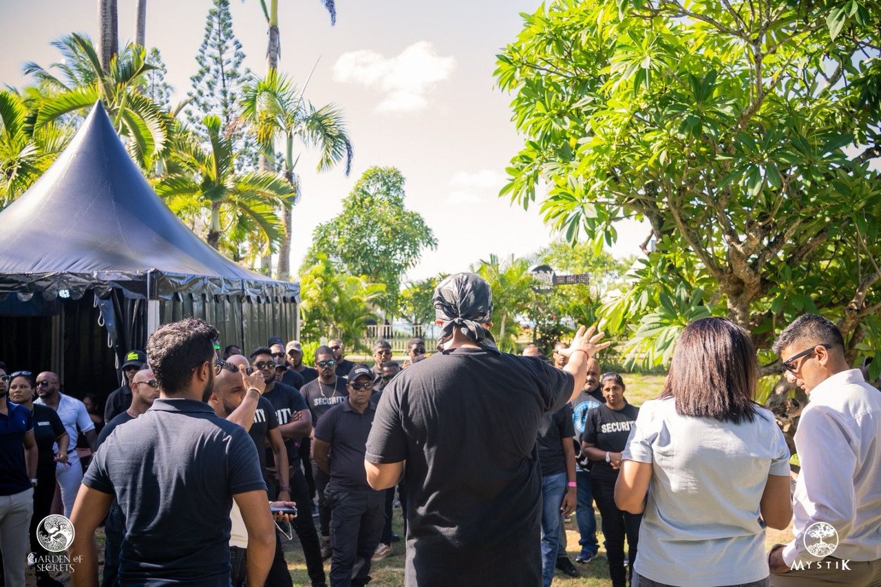 Event coordinator addressing a group of security crew in a garden production area ahead of the festival