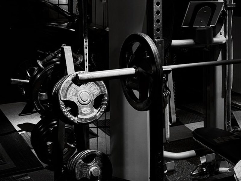 Black and white photo of a home gym power rack with a loaded barbell and weight plates